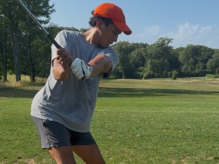 Alex taking a golf swing on the course